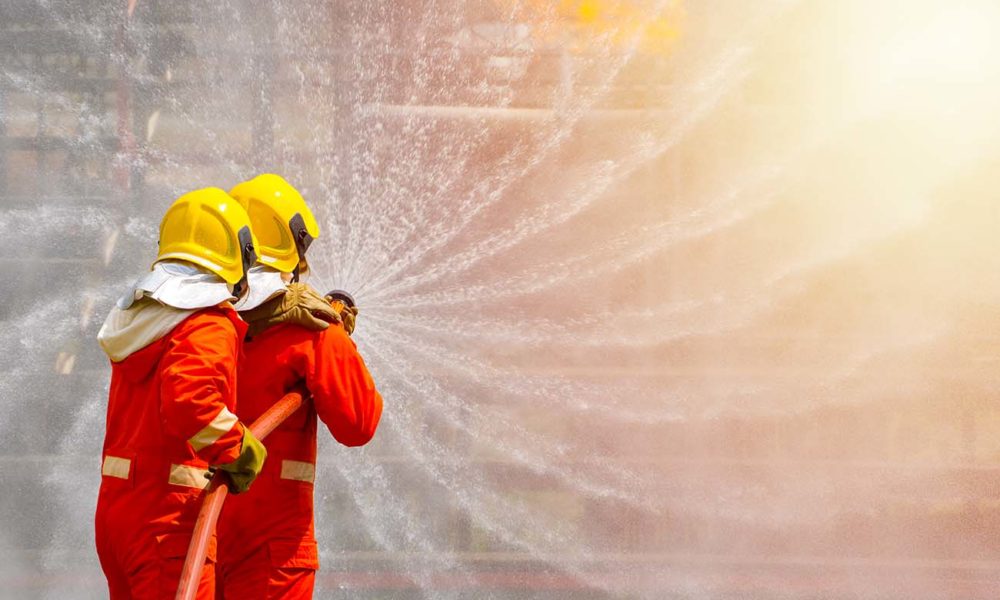 Two brave firefighter using extinguisher and water from hose for fire fighting, Firefighter spraying high pressure water to fire, Firefighter training with dangerous flames, Copy space-Image